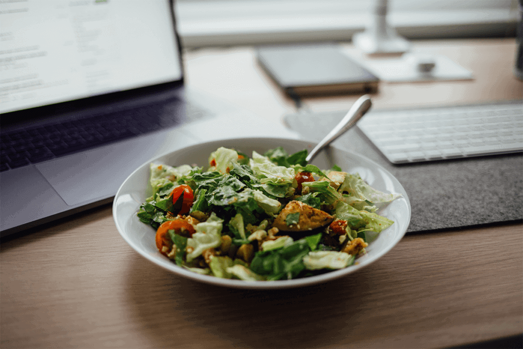 salad on desk next to laptop and keyboard
