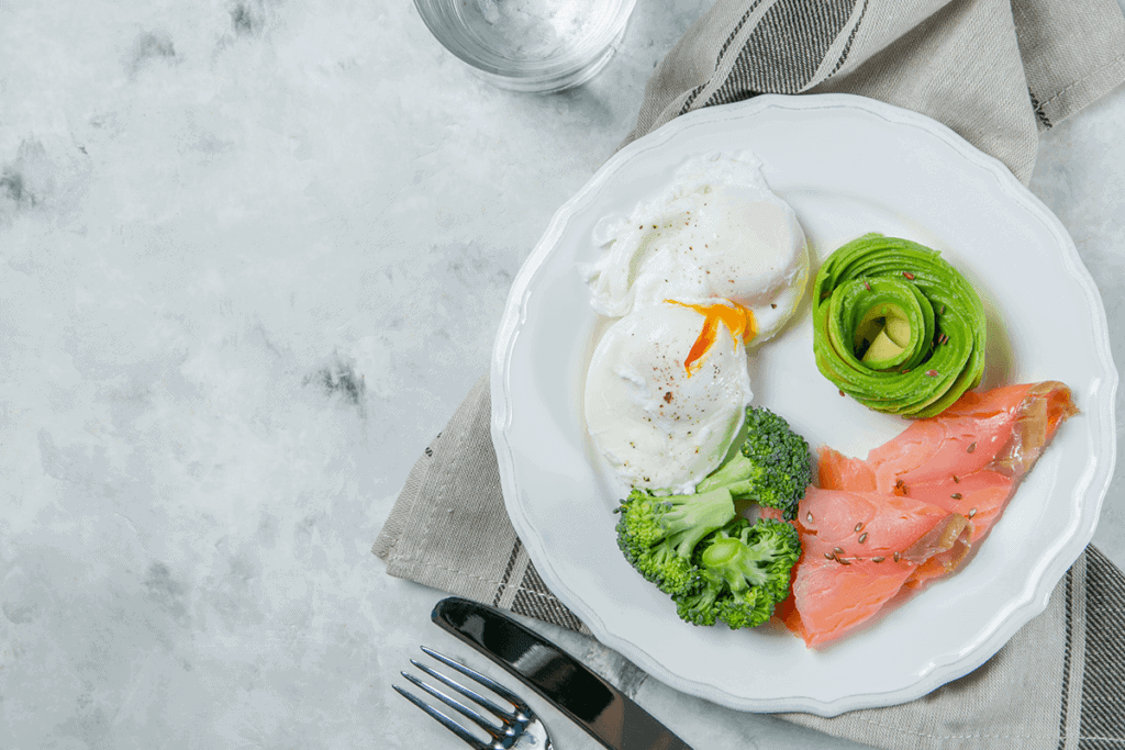 plate of food containing two poached eggs, a few broccoli florets, sliced avocados, and meat, represents a balanced weight loss diet