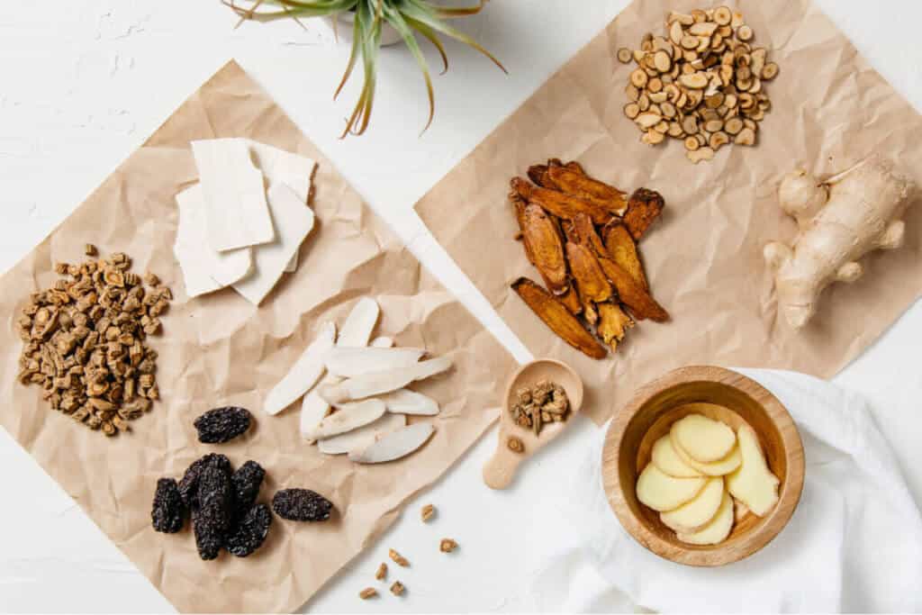 Flat lay of medicinal herbs on brown paper over a white background