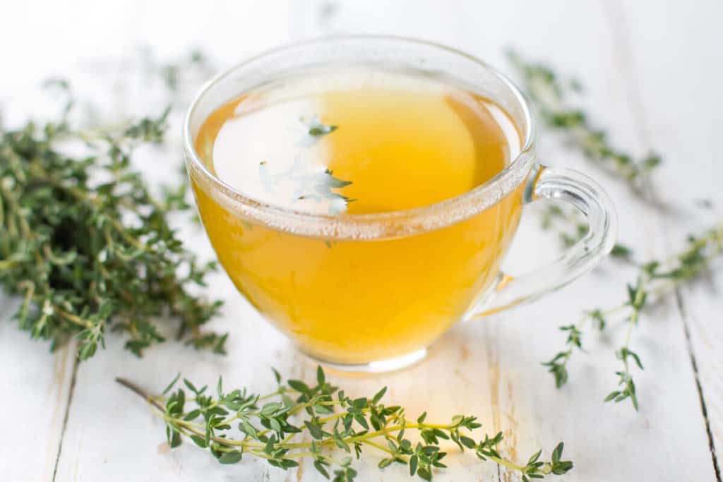 Herbal tea and stalks of herbs on a wooden table