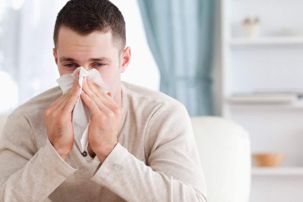 man blowing his nose into a tissue