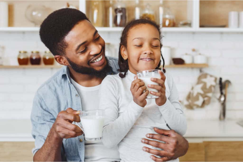 Man and child holding glasses of milk