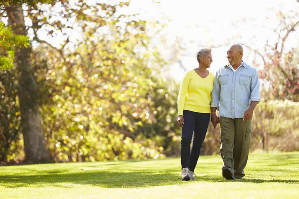 Couple walking through a park in the sunshine