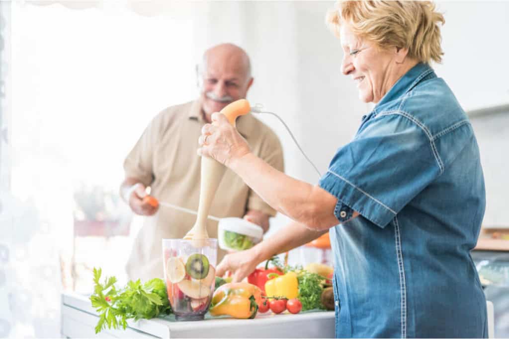 man and woman in the kitchen making juice from raw fruits