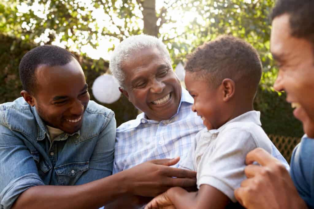 four males young and old sitting around and smiling