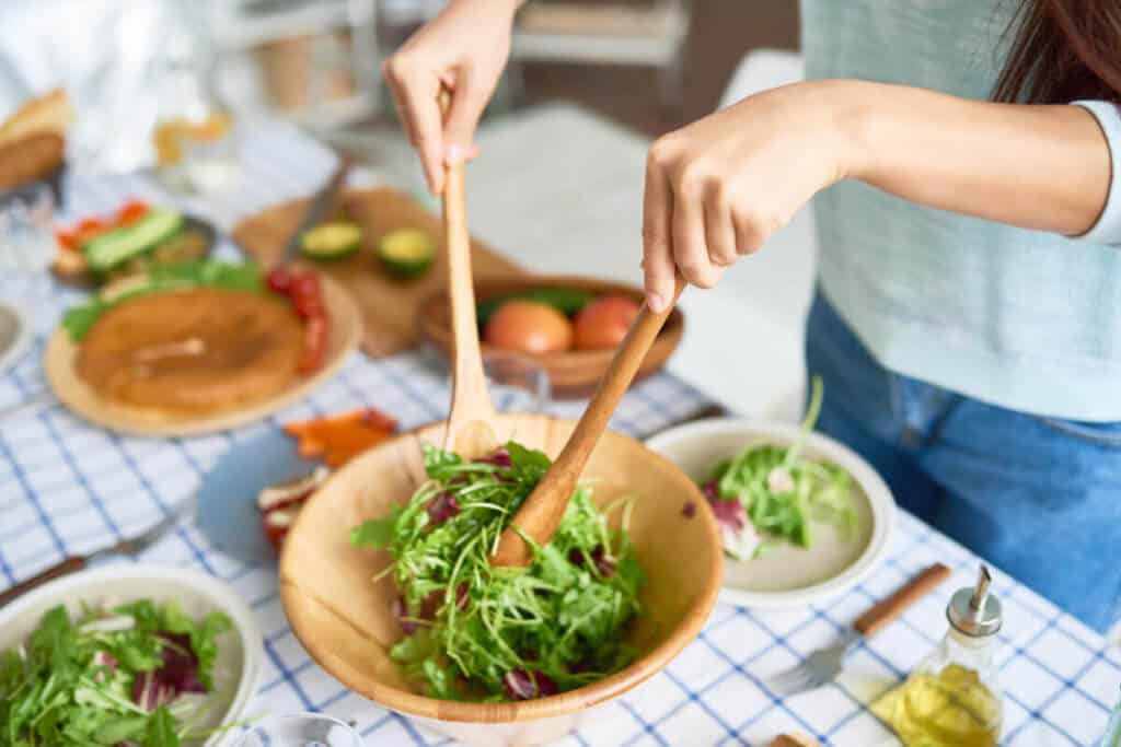 woman making a salad in brown bowl