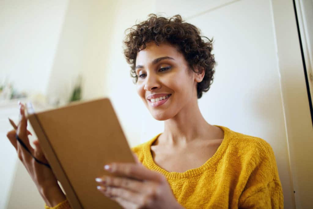 woman reading a journal and smiling