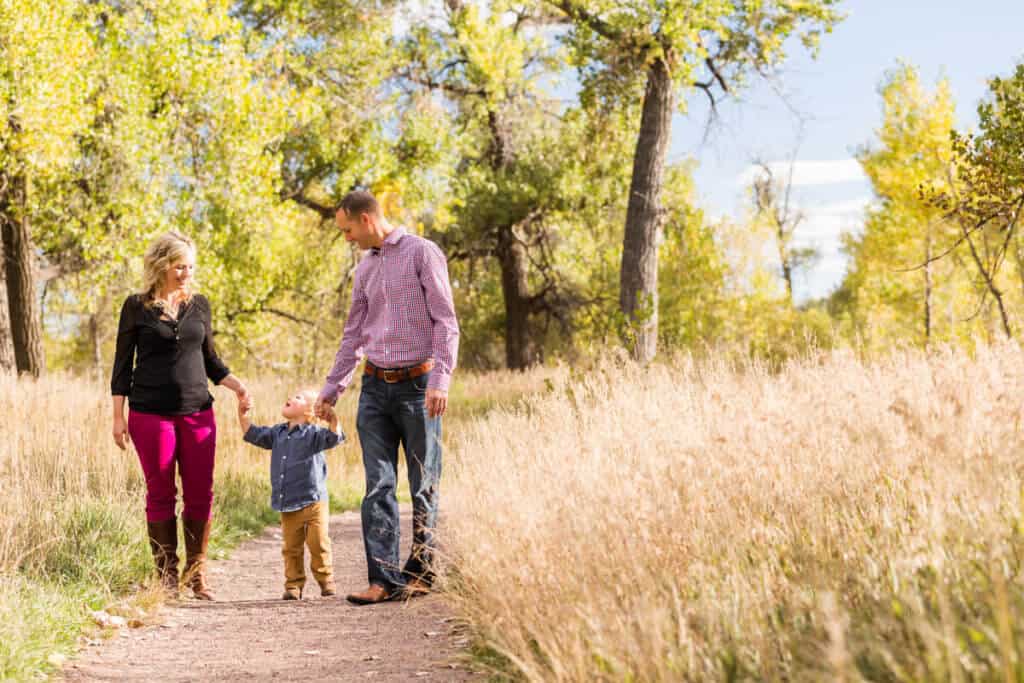 Young family walking through a park in early autumn.