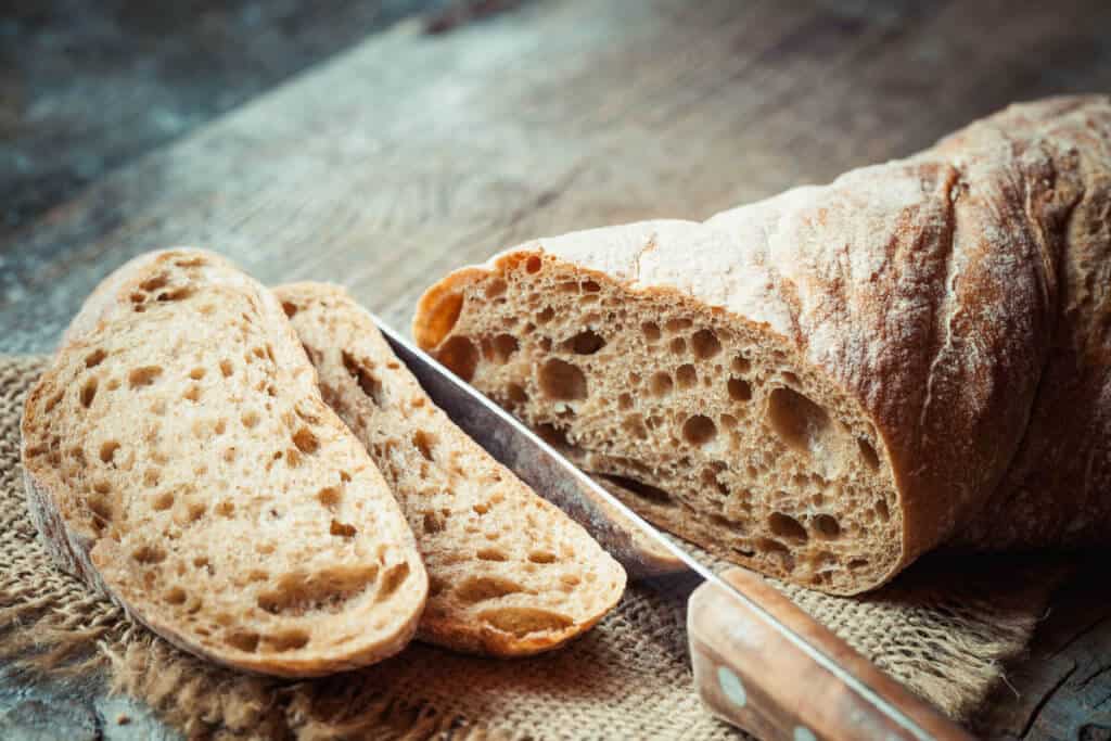 Sliced fresh bread and bread knife on a rustic cutting board