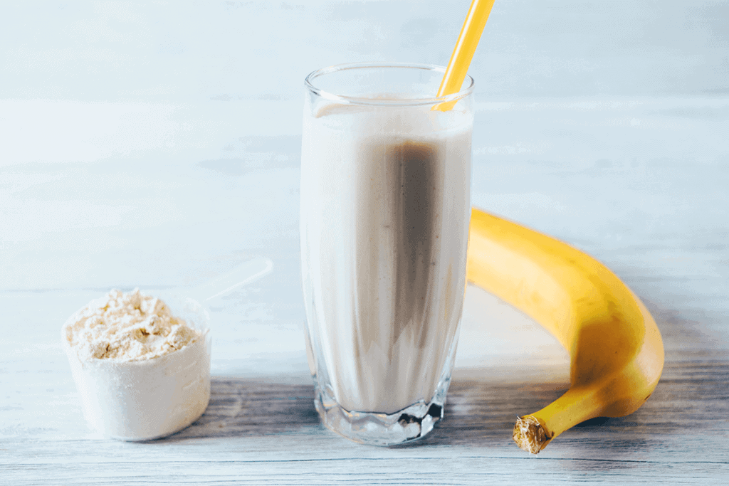 calcium powder next to a glass of milkshake with yellow straw and a banana