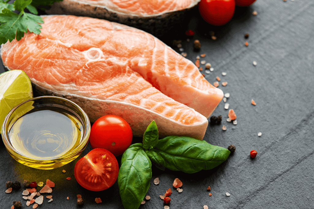 Salmon steaks with oil and vegetables on a grey backdrop