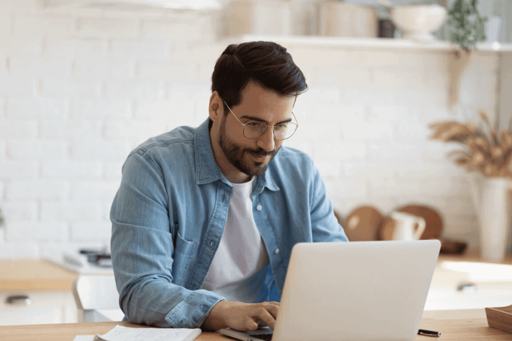 man in his kitchen looking at something on him laptop