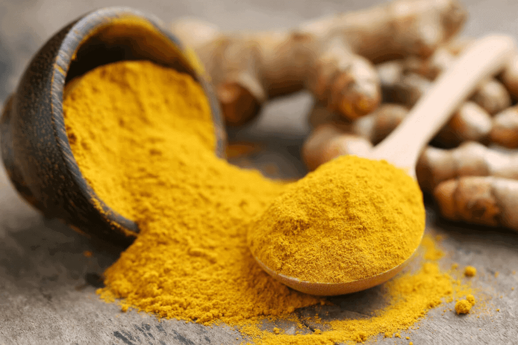 Turmeric powder and fresh turmeric on wooden background.