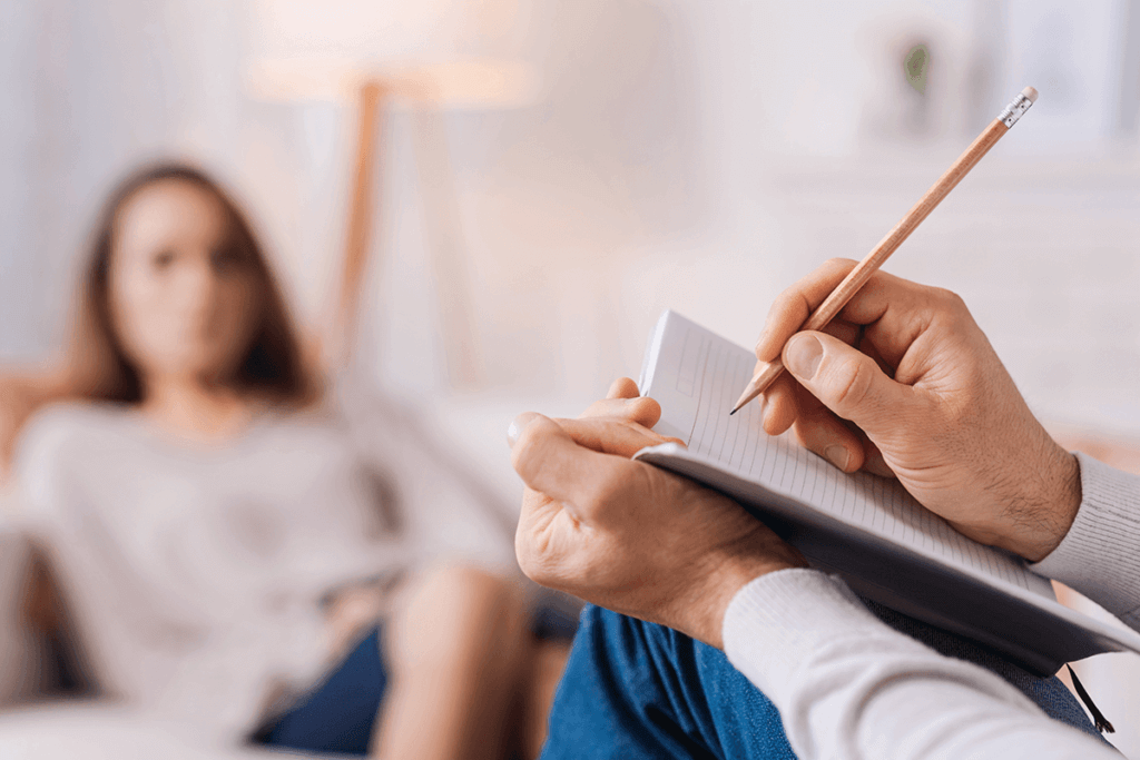 practitioner writing in a notebook while patient is speaking