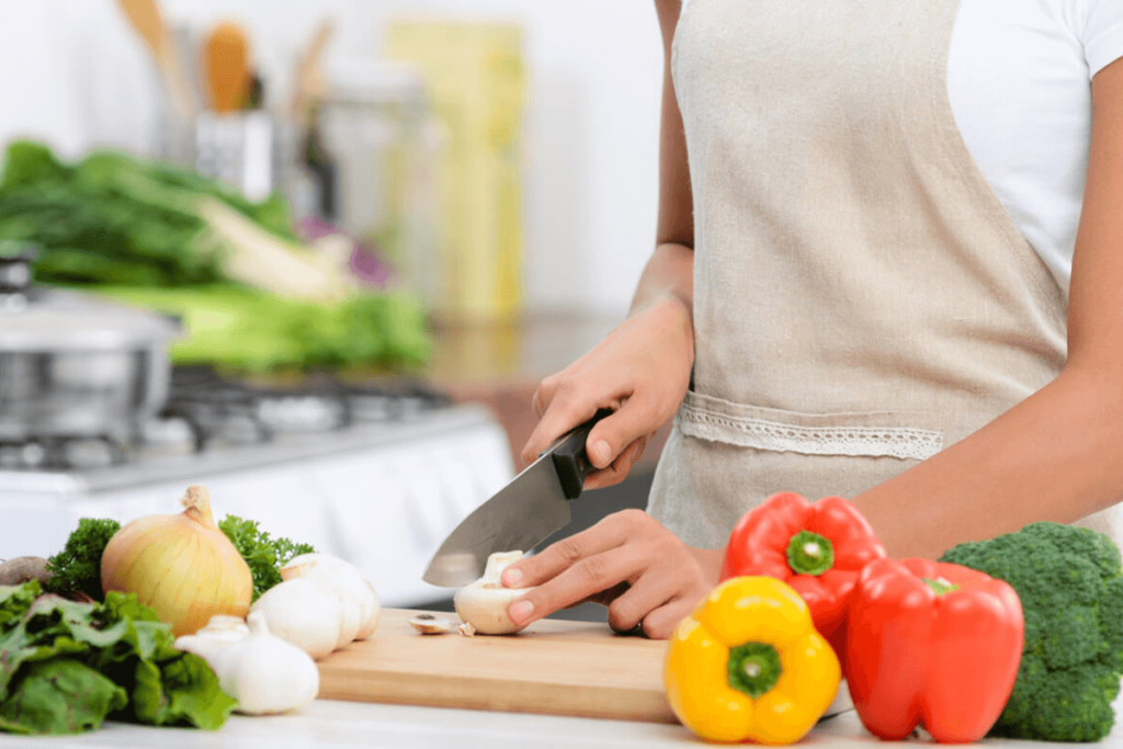 person cutting up fresh mushrooms and vegetables