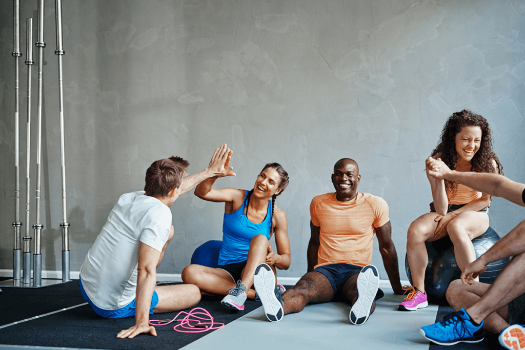 group of people sitting on the gym floor after a workout