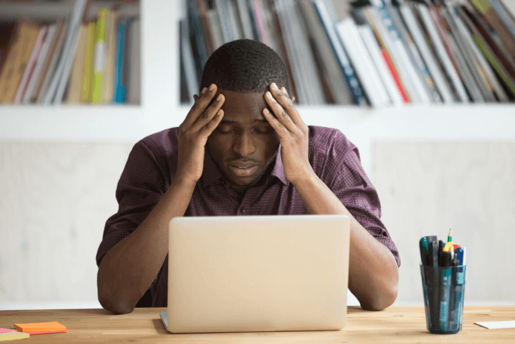 male looking at a laptop with hands on his head